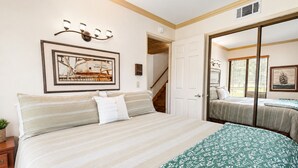 A bedroom with a large bed, a framed picture on the wall, a staircase, and a door leading to another room. - Lakefront Viking Oasis Condo - Lakefront, Indoor Pool, Hot Tub (Big Bear Lake)