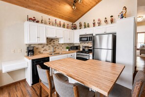 Eine moderne Küche mit weißen Schränken, einer Holz Arbeitsplatte und einem Edelstahlkühlschrank.