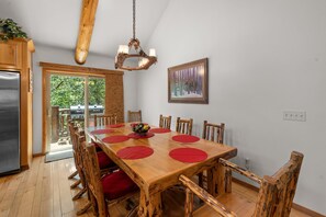 Een eethoek met een houten tafel, rode placemats en houten stoelen.