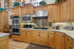 Una cocina con gabinetes de madera, electrodomésticos de acero inoxidable y salpicadero de azulejos.