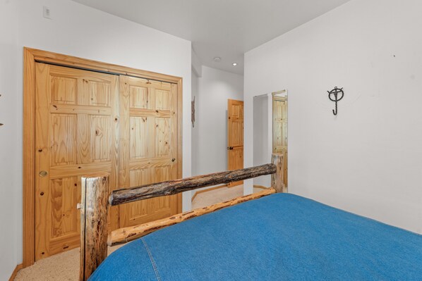 Un dormitorio con estructura de cama de madera, colchón azul y armario de madera.
