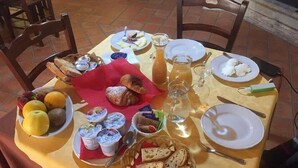A table set with breakfast items including bread, fruits, yogurt, and a croissant. - La Casa Del Priore (Patti)
