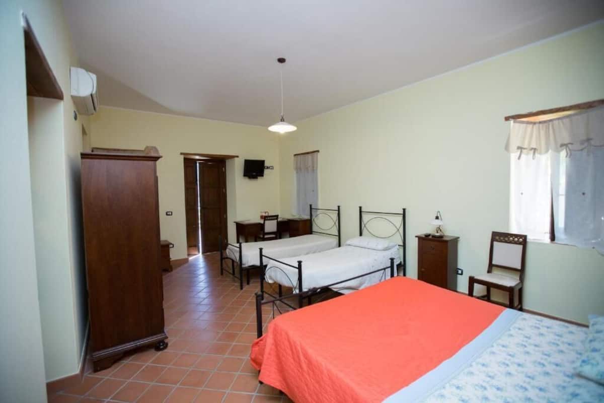 A bedroom with two single beds, a wooden wardrobe, a desk, and a chair.