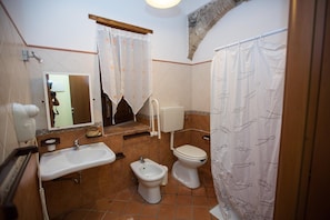 A bathroom with a sink, bidet, toilet, and a mirror.