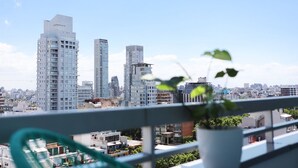 A cityscape with high-rise buildings and a balcony with a potted plant.