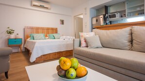 A bedroom with a bed, bedside table, and a bowl of fruit on a table.