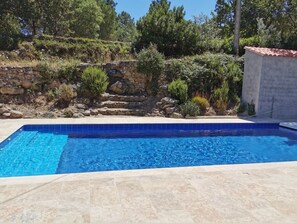 Ein Schwimmbad mit einer Steinmauer und Vegetation im Hintergrund.