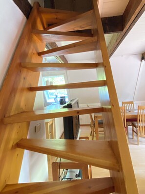 A wooden staircase in a room with a kitchen area visible in the background. - Cottage with large terrace in the vacation park at the Twistesee, Bad Arolsen (Bad Arolsen)