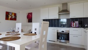 A modern kitchen with white cabinets, a stainless steel oven, and a coffee maker on the counter.