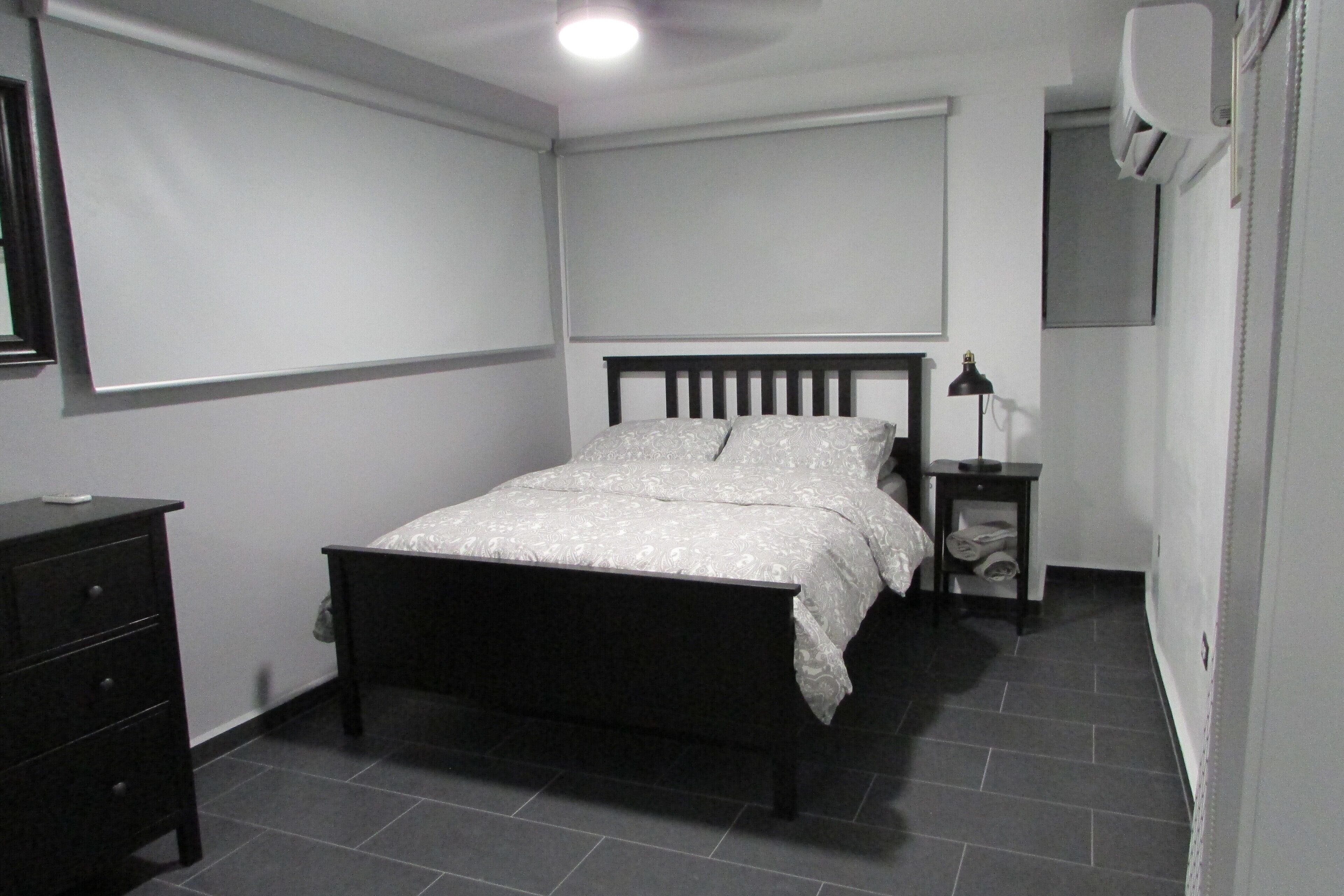 Un dormitorio con cama, mesita de noche, cómoda y ventilador de techo.