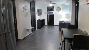 A compact kitchen with a refrigerator, a dining table with chairs, a sofa, a television, and a clock on the wall. - Perfect for relax time (La Parguera)