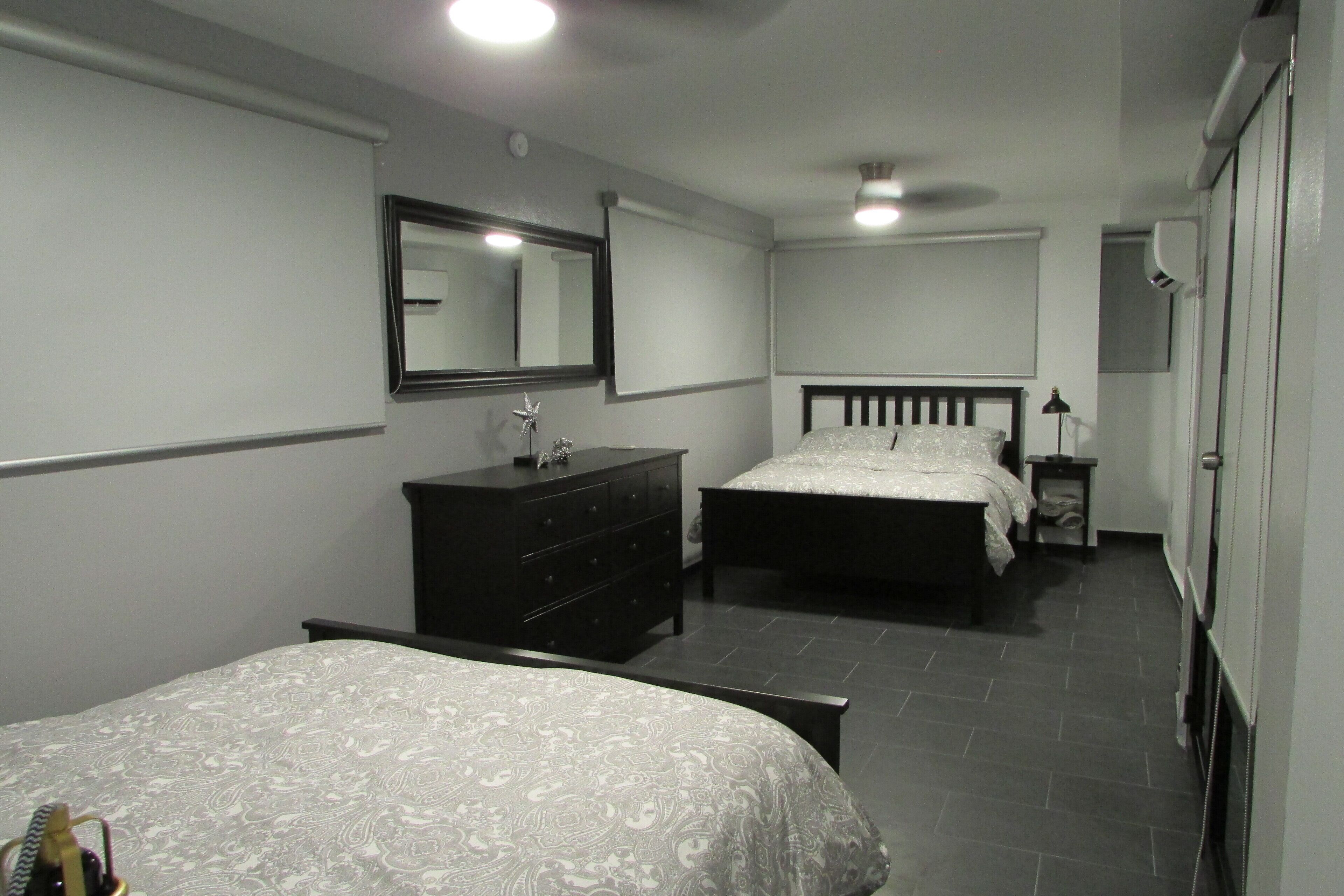 A bedroom with two beds, a dresser, a mirror, and a bedside table.