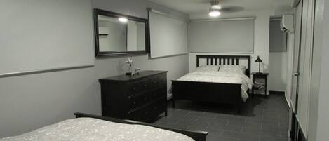 A bedroom with two beds, a dresser, a mirror, and a bedside table.