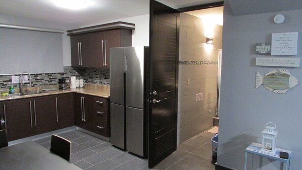 A modern kitchen with dark cabinets, a stainless steel refrigerator, and a tiled backsplash. - Perfect for relax time (La Parguera)