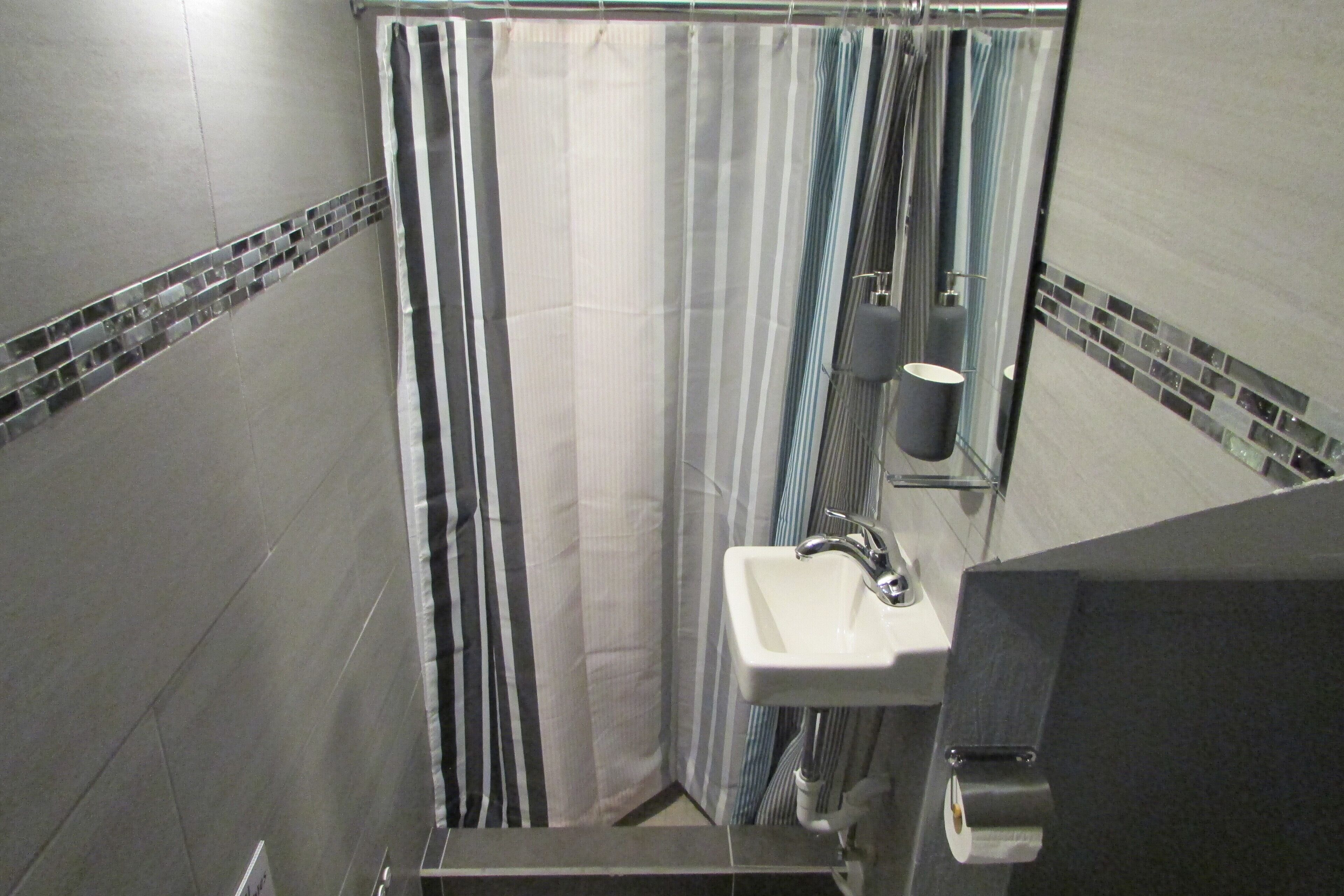A bathroom with a shower curtain, a sink, and a mirror.