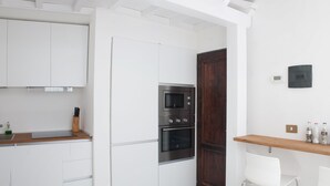 A modern kitchen with white cabinets, a wooden countertop, a built-in oven, and a microwave. - La Sapienza Di Al (Siena)
