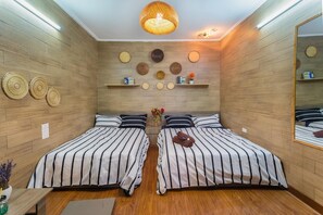 A room with two beds, wooden walls, a hanging light fixture, and wall-mounted shelves with decorative items. - Hanoi Lotus Guest House (Hanoi)
