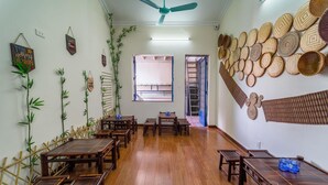 A room with wooden tables and chairs, bamboo decorations, and woven baskets on the walls. - Hanoi Lotus Guest House (Hanoi)