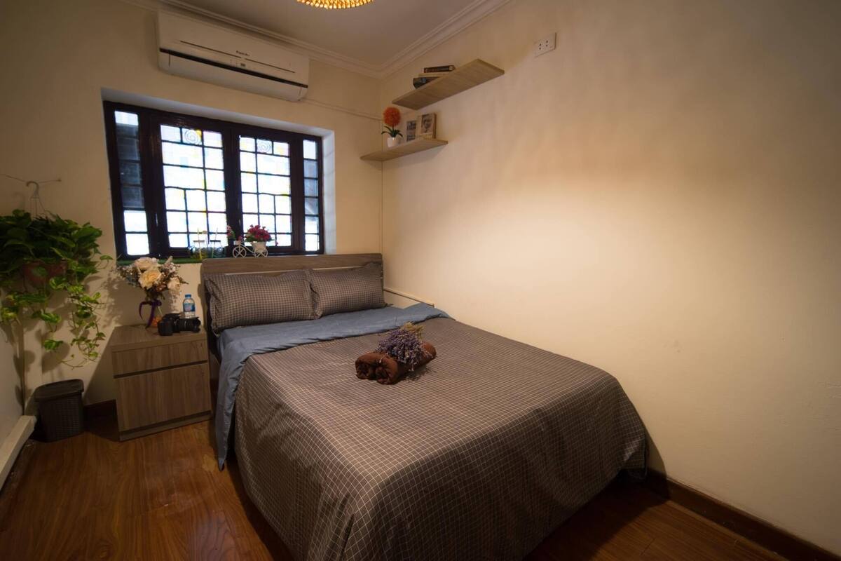 A neatly arranged bedroom with a bed, bedside table, and a window with a view.