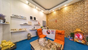 A room with a brick wall, a sofa, a coffee table with jewelry, and shelves with decorative items. - Hanoi Lotus Guest House (Hanoi)