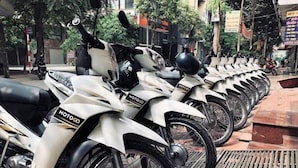 A row of white motorcycles parked on a tiled pavement. - Hanoi Lotus Guest House (Hanoi)