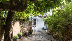 A stone-paved courtyard with potted plants, a white door, and a ladder leaning against a wall. - Birch at Ship St Gardens (Brighton)