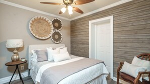 A bedroom with a bed, a wooden ceiling fan, a round wall decoration, and a door. - Monroe property near Antiques and Football (Monroe)