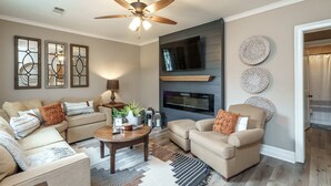 A living room with a ceiling fan, a fireplace, and a television. - Monroe property near Antiques and Football (Monroe)