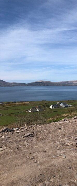 A coastal landscape with a body of water, distant hills, and scattered buildings.