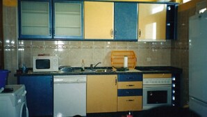 A compact kitchen with a microwave, stove, and sink. - 100 m2 apartment in Olhão, central, for rent. (Olhão)