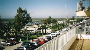 A parking lot with multiple cars, palm trees, and a clear view of the surrounding landscape. - 100 m2 apartment in Olhão, central, for rent. (Olhão)