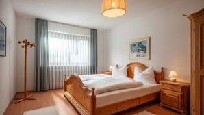 Un dormitorio ordenado con una cama de madera, mesitas de noche con lámparas, una lámpara de pie y un cuadro en la pared.