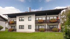 Un edificio de dos pisos con balcones, cada uno decorado con macetas de flores.