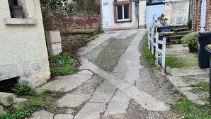 A narrow, gravelly pathway leading to a building with a white door and a small window.