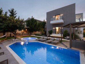 Uma área de piscina moderna ao ar livre, com hidromassagem, espreguiçadeiras e um espaço de refeições.