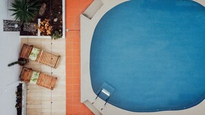 Vista aérea de una piscina con sillas de descanso y un deck empinado.