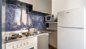 A compact kitchen with a stove, microwave, and a refrigerator. - Rooms Piramide (Rome)