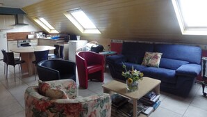 A compact living space with a kitchenette, a dining area, and a seating area with a sofa and chairs. - .2 STAR B&B by the sea (saint pol de léon)