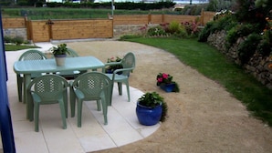 An outdoor patio with a table and chairs, surrounded by potted plants and a gravel area. - .2 STAR B&B by the sea (saint pol de léon)