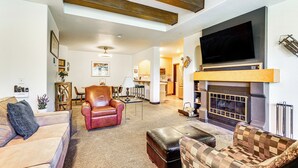A spacious living room with a fireplace, leather sofas, and a television mounted on the wall.