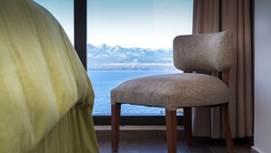 Una habitación con vistas a montañas y una silla cerca de la ventana.