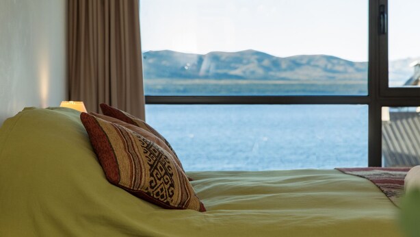 Una cama con vista a las montañas a través de una ventana.
