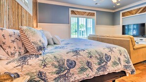 A bedroom with a large bed, a ceiling fan, a TV, and a window with blinds. - Cottage w/ Porch - 3 Min Walk to Bay St Louis (Bay St. Louis)