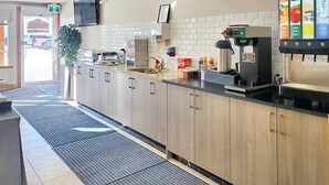 Una cocina moderna con cafetera, pileta y salpicadero de azulejos.