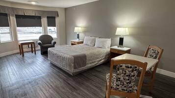 A hotel room with a large bed, two bedside tables with lamps, a chair, and a desk.
