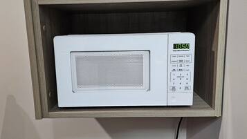 Un horno microondas instalado en un estante de madera sobre un enchufe de pared.