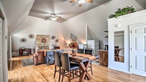 Un comedor amplio con una mesa y sillas de madera, un ventilador de techo y una pared decorativa.