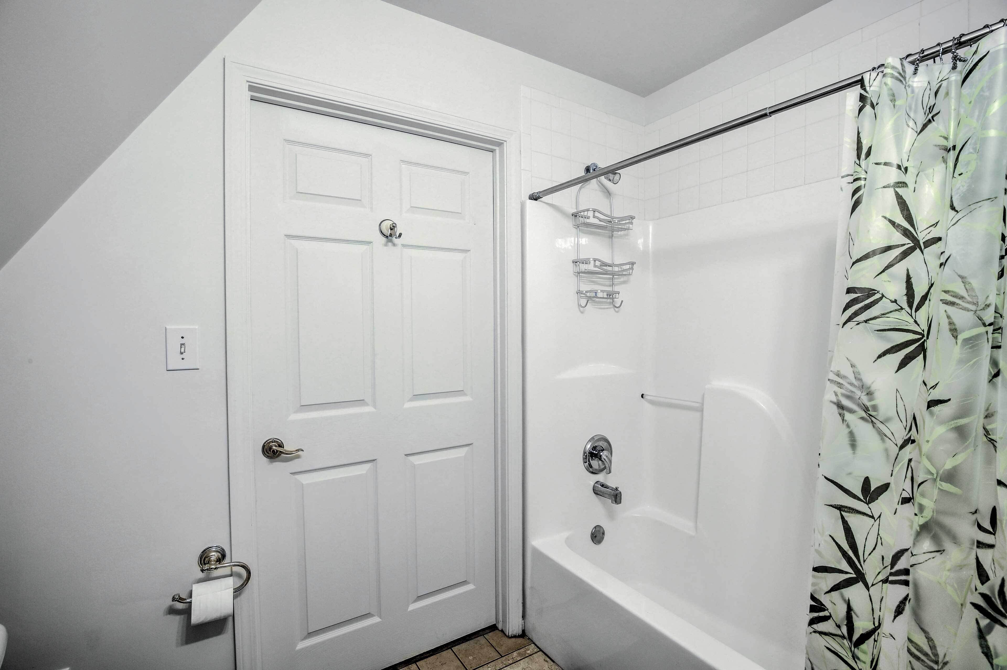 Une salle de bain avec une porte blanche, une baignoire avec un rideau de douche et un porte-serviettes.