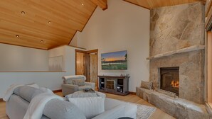 A spacious living room with a stone fireplace, a large painting, and a cozy seating area.