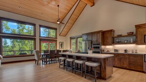 A spacious kitchen with wooden cabinets, a large island with stools, and a dining area with chairs.